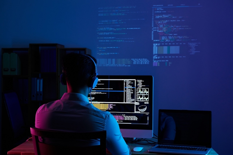 Developer in front of laptop wearing headphones